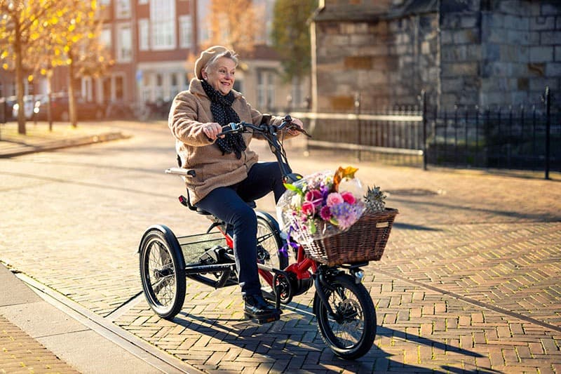 Huka Cortes XS driewielfiets voor klein volwassenen of kinderen sfeerfoto  onderweg met bloemen op de rode fiets