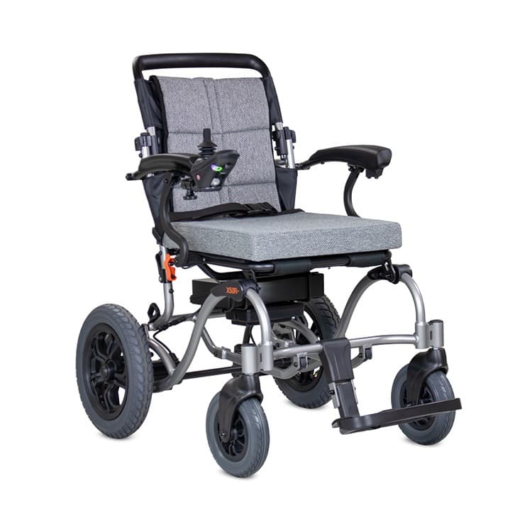 Excel X50R+ elektrische rolstoel met brede centrale voetsteun, heupgordel en joystick bediening en zwart en zilver frame met lichtgrijze bekleding en stevige rugleuning
