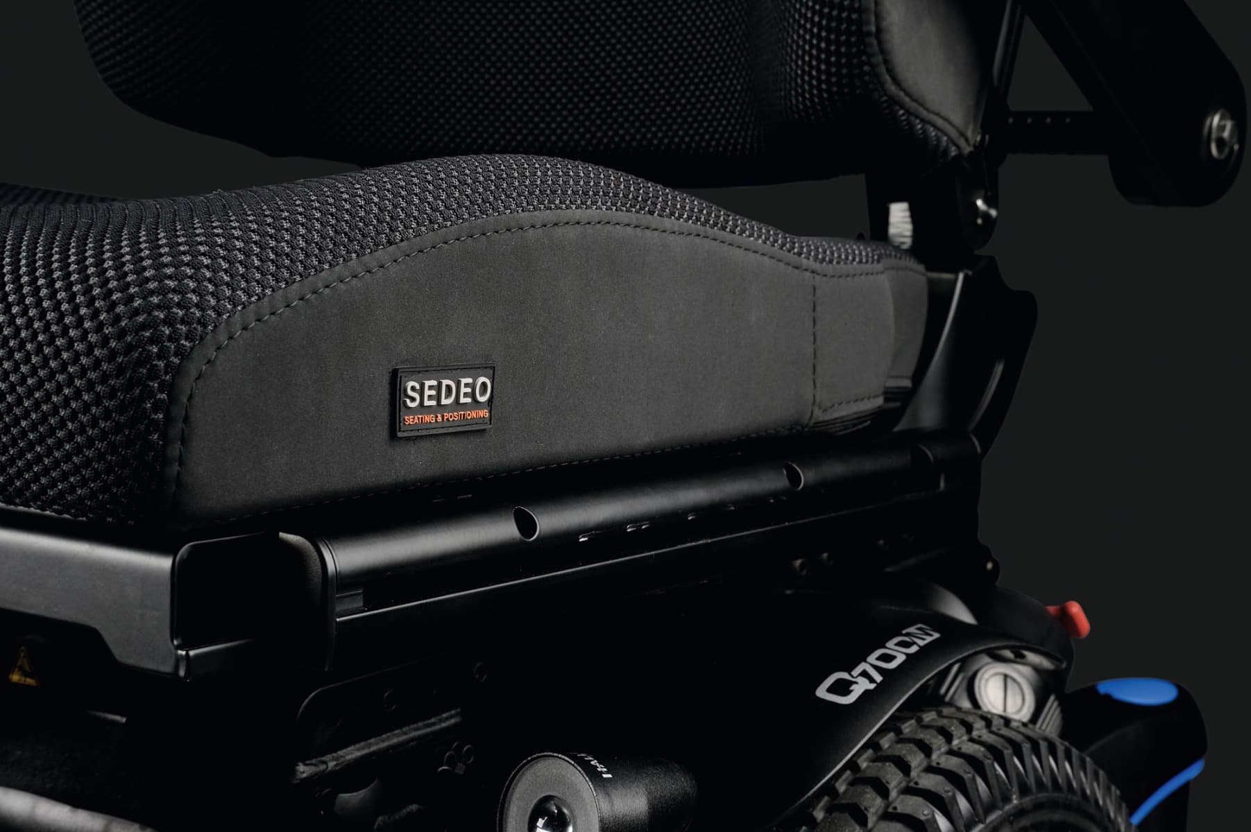 Quickie Q700 elektrische rolstoel maatwerk met grote voetsteunen, ergnomische zitting en hoofdsteun en joystick bediening beeld met midwielmotor detailfoto comfortabele sedeo zitting en midwielaandrijving